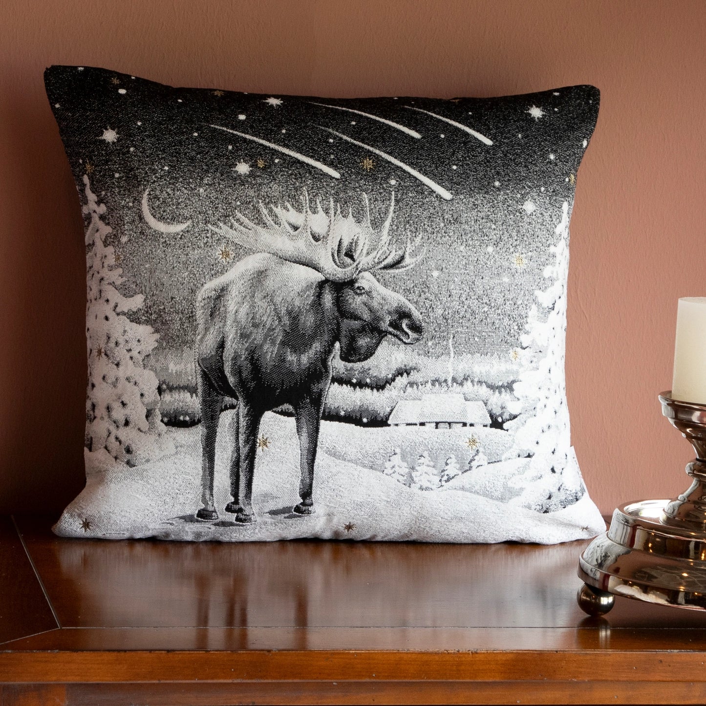 Quadratische Chenille Kissenhülle 45x45 cm in Schwarz-Weiß mit einem majestätischen Elch in einer verschneiten Winterlandschaft unter einem Sternschnuppen-Himmel auf einer Holzkommode