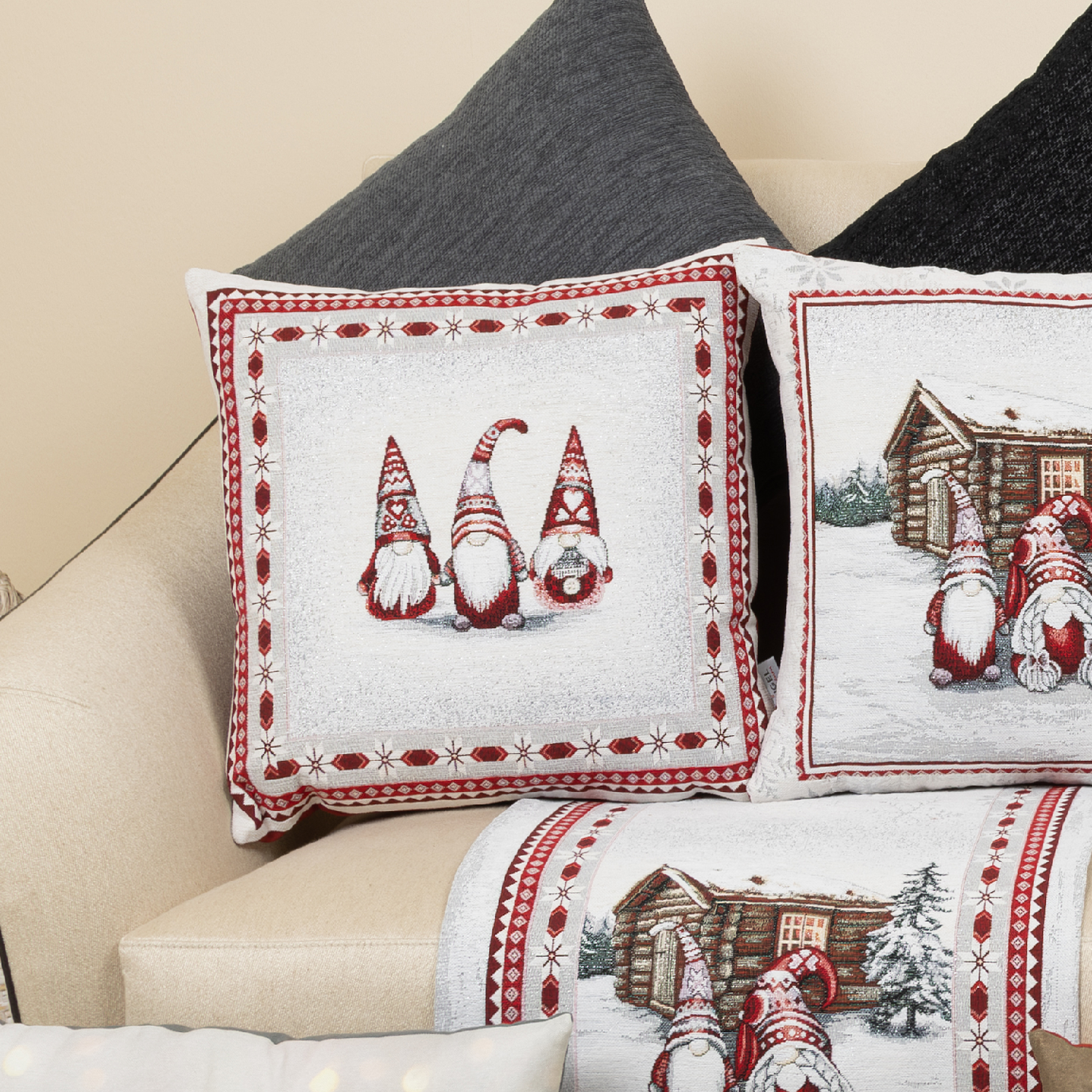 Gobelin-Kissenhülle mit drei Wichtelfiguren mit rot-weiß gemusterten Mützen, umrahmt von einem festlichen Musterrahmen auf hellem Sofa, mit anderen weihnachtlichen Kissen.