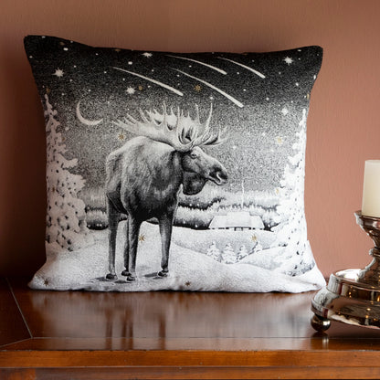 Quadratische Chenille Kissenhülle 45x45 cm in Schwarz-Weiß mit einem majestätischen Elch in einer verschneiten Winterlandschaft unter einem Sternschnuppen-Himmel auf einer Holzkommode