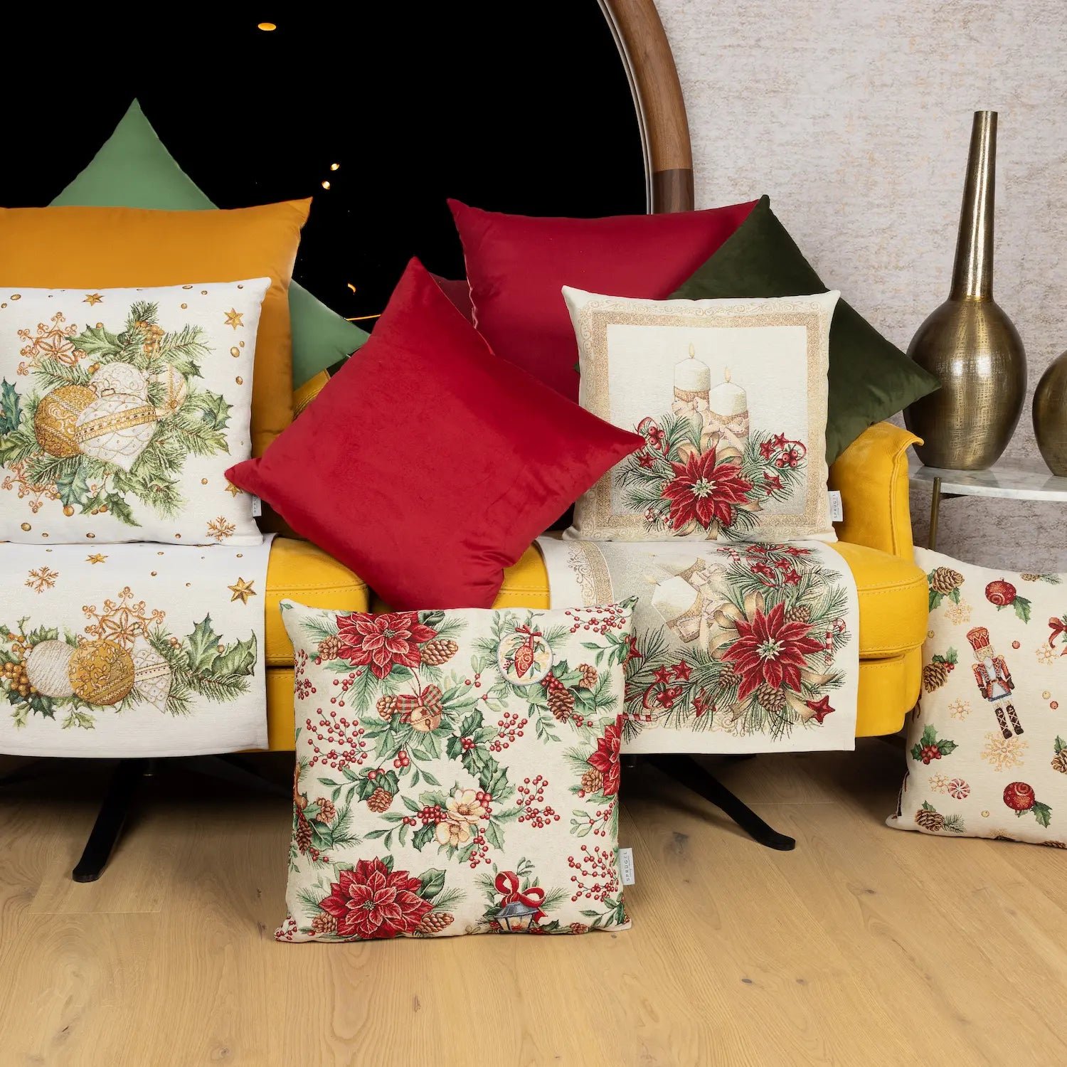 Festlicher Gobelin-Tischläufer, rechteckig, mit roten Weihnachtssternen, grünen Tannenzweigen und goldener Zierbordüre liegt unter anderen weihnachtlichen Kissen auf einem gelben Sofa